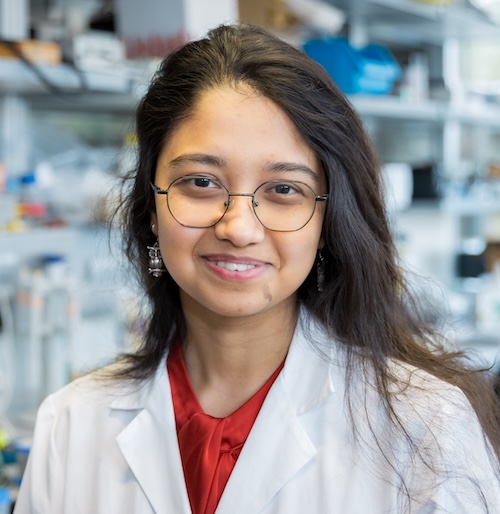 Photo of a woman with glasses wearing a lab coat.